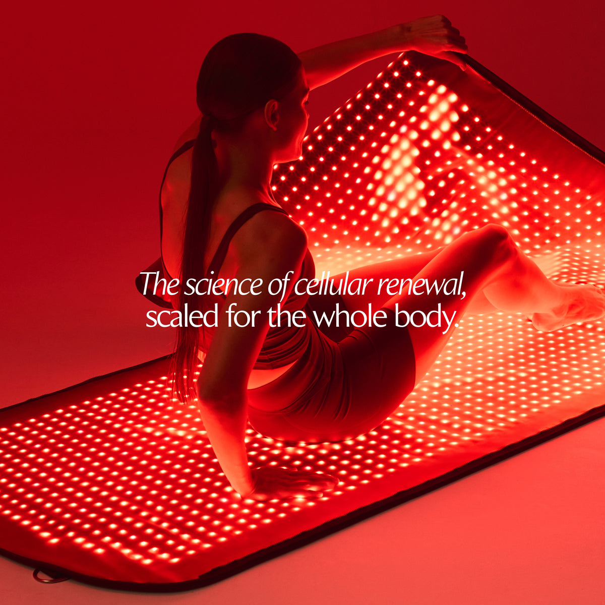 Mujer sentada en una esterilla LED Restora+ encendida, levantando el panel superior de la cápsula