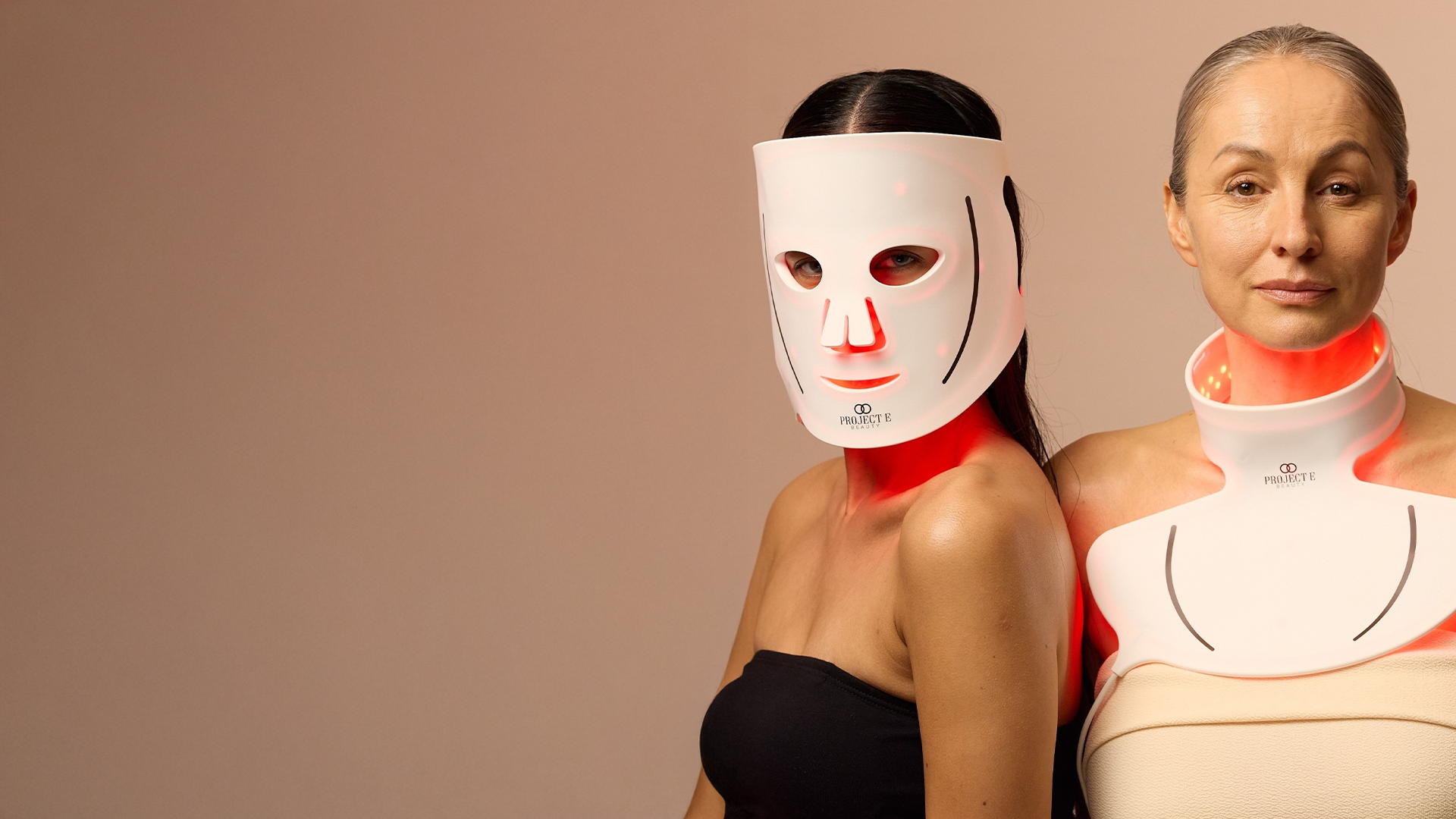Woman using red light neck attachment beside another woman in LED face mask